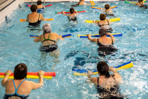 Grupo de señoras mayores realizando ejercicios dentro de la piscina