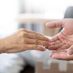 Manos de cuidador extendida hacia la mano de un anciano