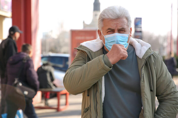Anciano tosiendo con mascarilla