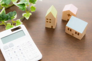 Calculadora con casas de madera representando subvencion a la vivienda